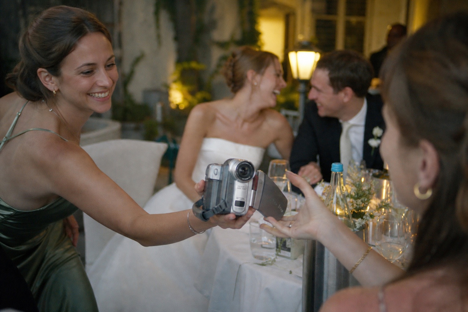 A wedding guest passing a small camcorder to another guest during the reception