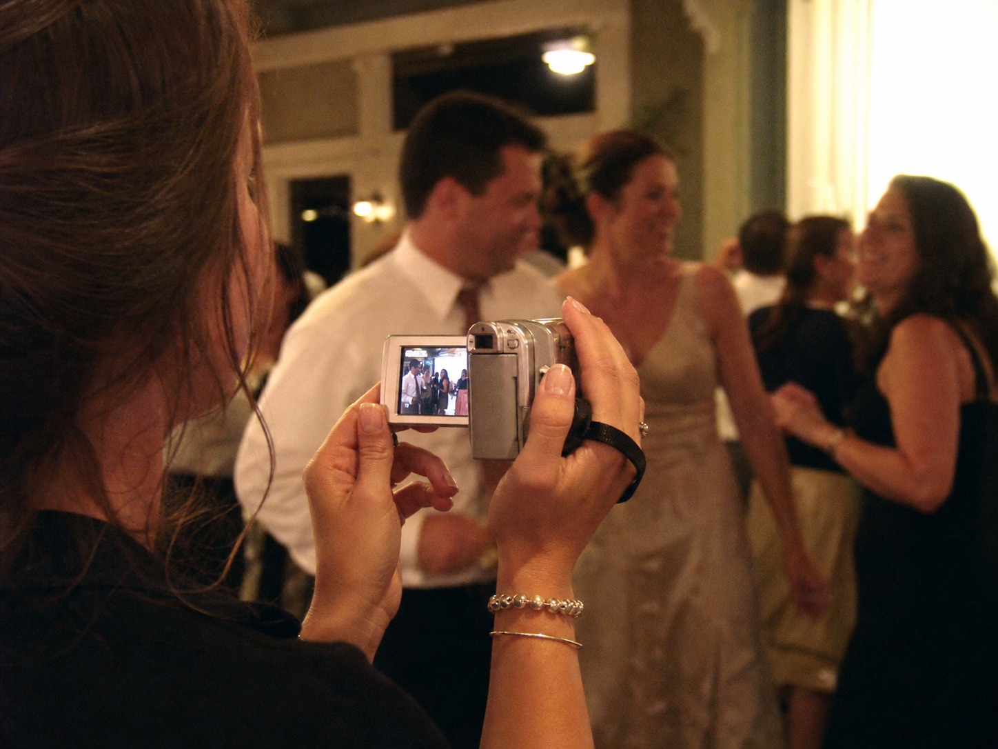 A wedding guest filming the reception with a small camcorder